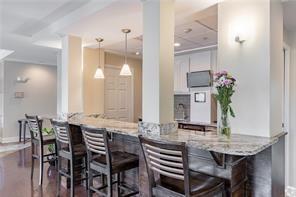 bar with white cabinets, dark hardwood / wood-style floors, pendant lighting, and light stone countertops