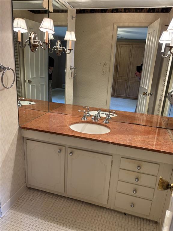 bathroom with tile patterned floors, wallpapered walls, a chandelier, and vanity
