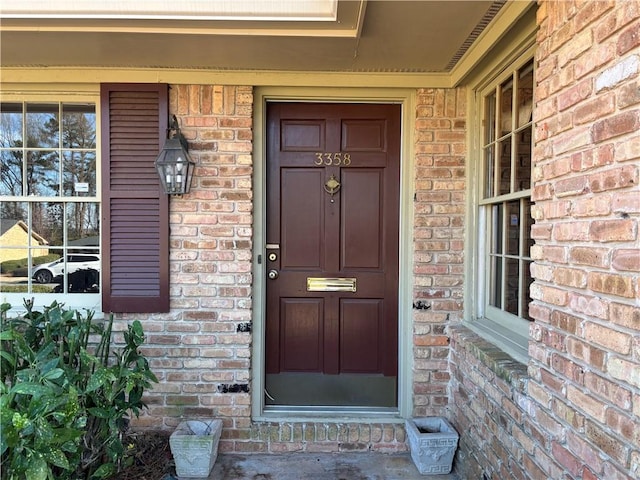 doorway to property with covered porch and brick siding