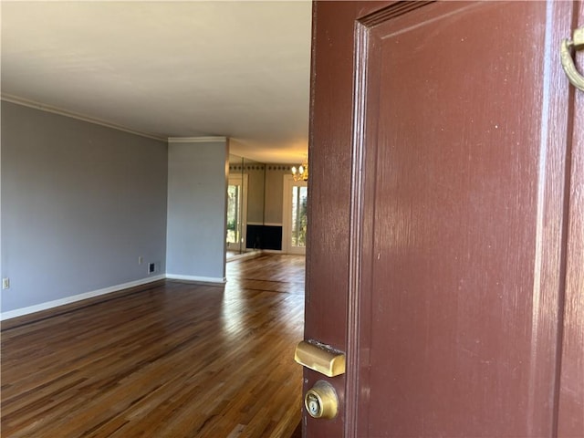interior space featuring an inviting chandelier, ornamental molding, dark wood-style floors, and baseboards