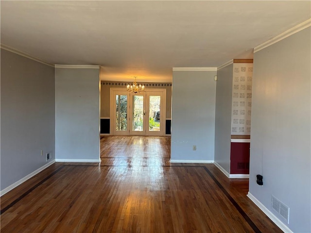 spare room featuring baseboards, visible vents, hardwood / wood-style flooring, and a notable chandelier