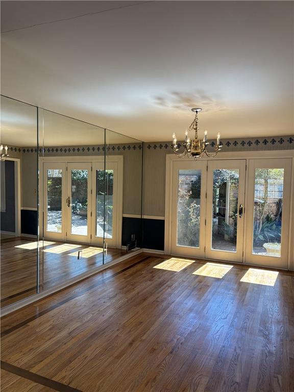 interior space featuring wood finished floors, a notable chandelier, french doors, and plenty of natural light