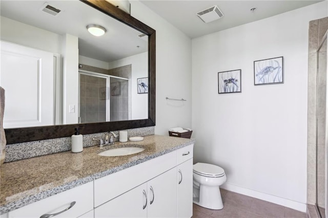 bathroom with a shower with door, vanity, tile patterned floors, and toilet