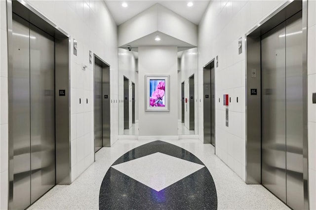 corridor featuring a package area, elevator, and tile walls