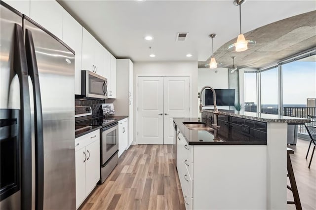 kitchen featuring appliances with stainless steel finishes, pendant lighting, and white cabinets