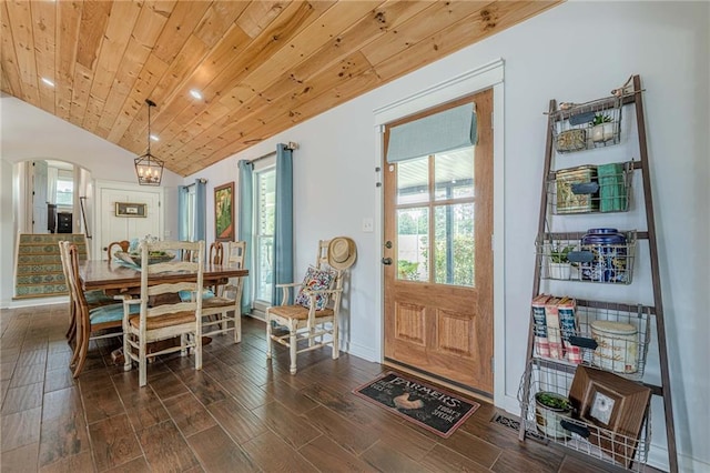dining area featuring arched walkways, vaulted ceiling, wooden ceiling, dark wood-type flooring, and baseboards