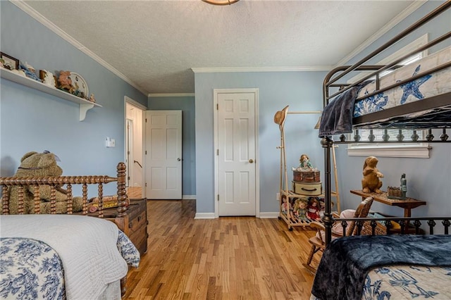 bedroom with light wood finished floors, a textured ceiling, crown molding, and baseboards