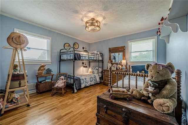 bedroom featuring crown molding, light wood-style flooring, and a textured ceiling