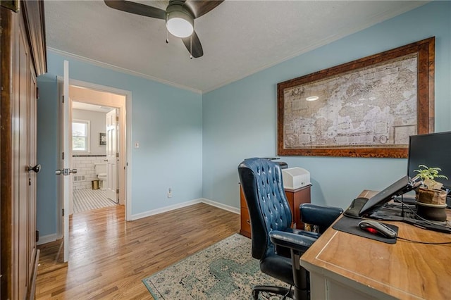 office area with crown molding, light wood-style flooring, a ceiling fan, and baseboards