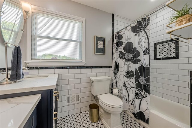 full bathroom featuring vanity, toilet, shower / bath combo, tile patterned flooring, and tile walls