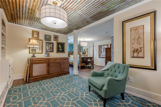 living area featuring baseboards, crown molding, and wood finished floors
