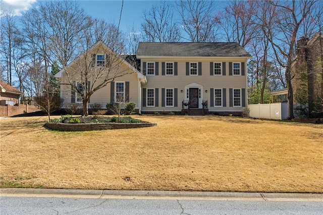 colonial inspired home featuring a front yard and fence