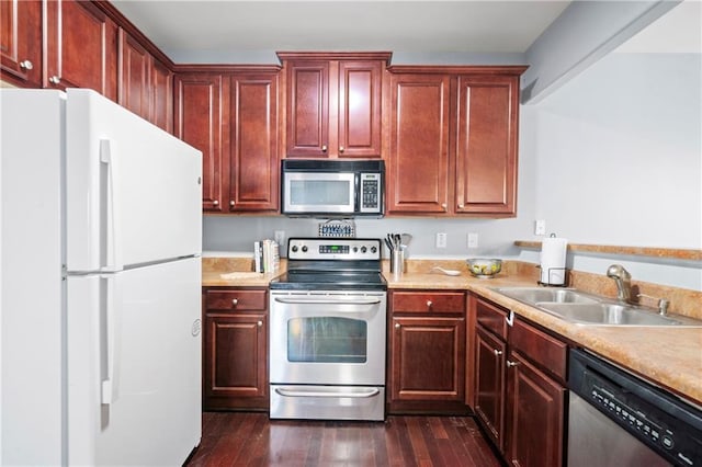 kitchen with appliances with stainless steel finishes, sink, and dark hardwood / wood-style flooring