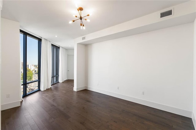 spare room with a notable chandelier, dark hardwood / wood-style floors, and expansive windows