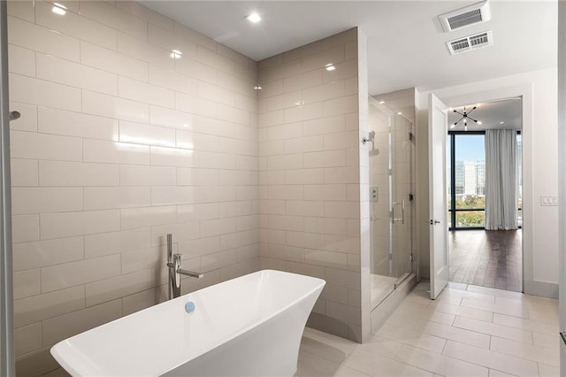 bathroom featuring hardwood / wood-style floors, plus walk in shower, and tile walls