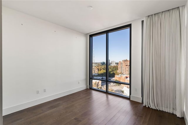 unfurnished room featuring a wall of windows and dark wood-type flooring