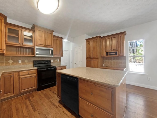 kitchen featuring brown cabinets, black appliances, wood finished floors, and a center island