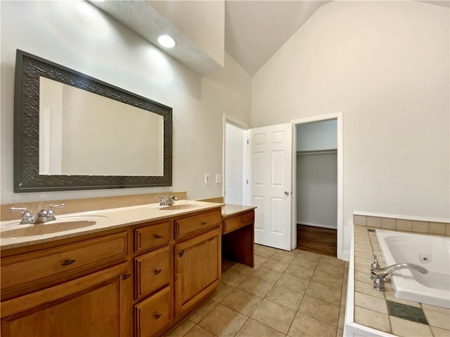 bathroom with a sink, a tub with jets, tile patterned floors, and vaulted ceiling