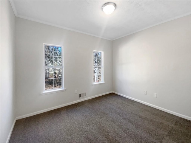 unfurnished room featuring visible vents, dark carpet, crown molding, and baseboards