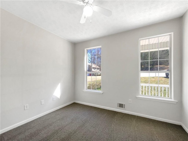 unfurnished room with dark colored carpet, visible vents, baseboards, and a textured ceiling