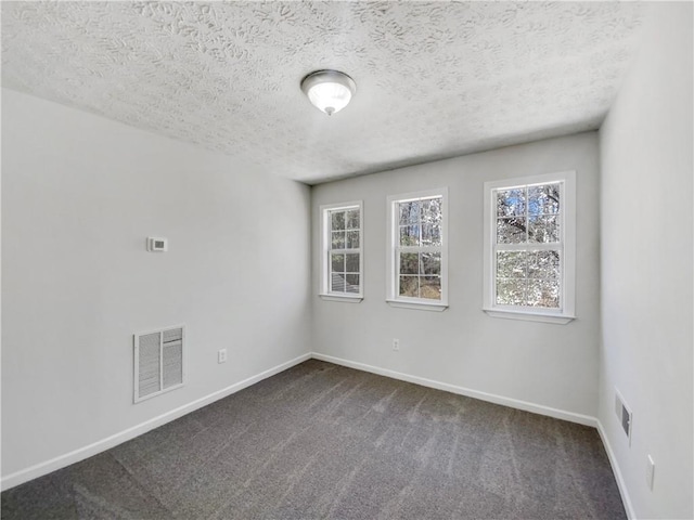 empty room with dark colored carpet, visible vents, and baseboards