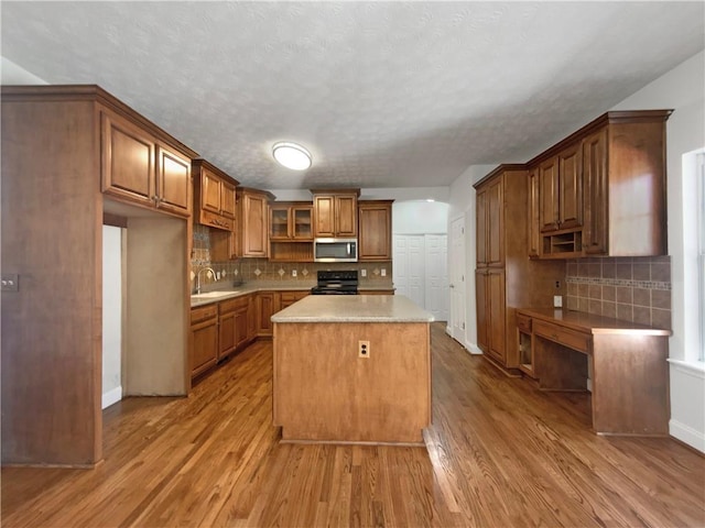 kitchen with stainless steel microwave, wood finished floors, electric range, and a sink