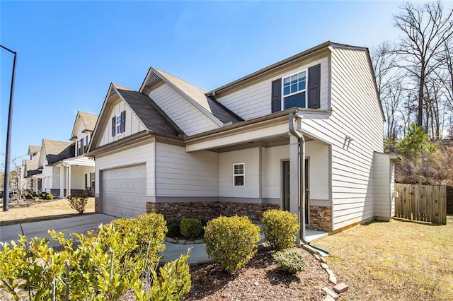 view of front facade featuring board and batten siding, fence, driveway, stone siding, and an attached garage