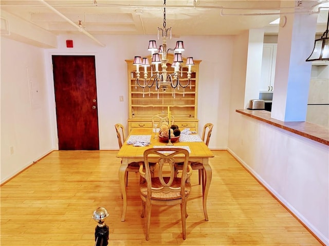 dining area featuring beam ceiling, light wood-type flooring, and a notable chandelier