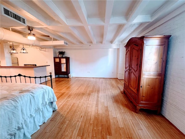 bedroom featuring beamed ceiling, refrigerator, light hardwood / wood-style flooring, and brick wall