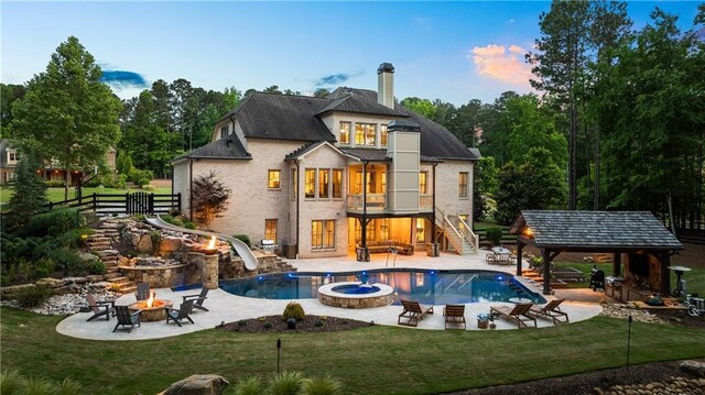 5330 Lake Redwine Cv NW, Acworth, GA 30101 - back of house at dusk with an outdoor fire pit, stairs, a chimney, a patio, and a pool with connected hot tub