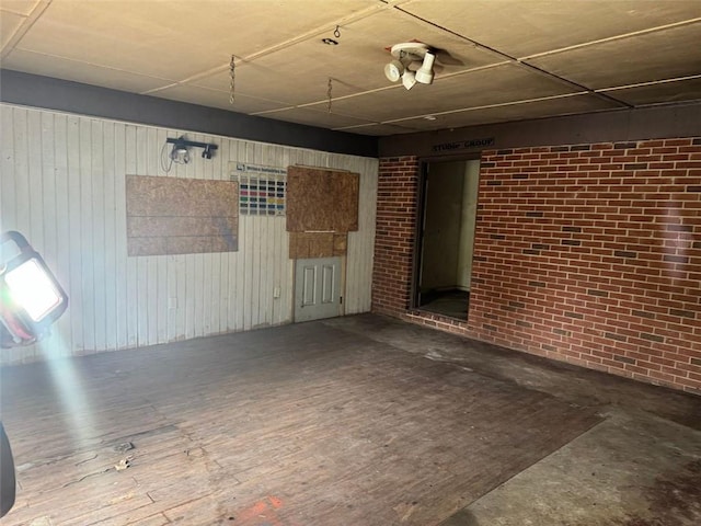 below grade area with wood-type flooring, wooden walls, and brick wall
