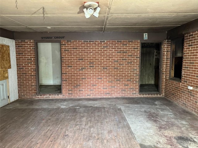 exterior space featuring brick wall and wood finished floors