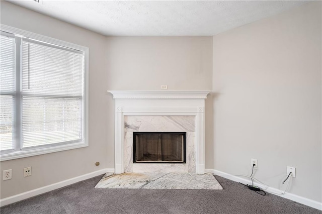 unfurnished living room featuring carpet, a textured ceiling, baseboards, and a premium fireplace