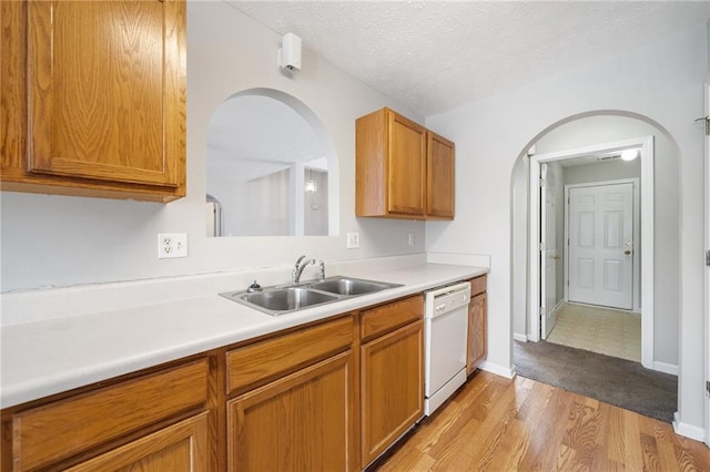 kitchen featuring light countertops, a sink, a textured ceiling, and dishwasher