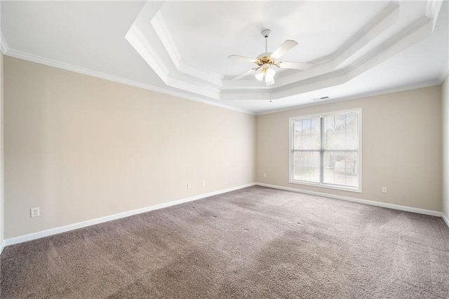 carpeted spare room featuring ceiling fan, ornamental molding, a raised ceiling, and baseboards