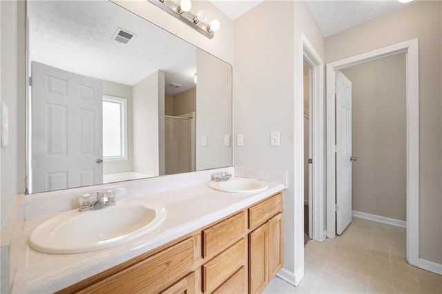 full bathroom featuring double vanity, a shower stall, visible vents, and a sink