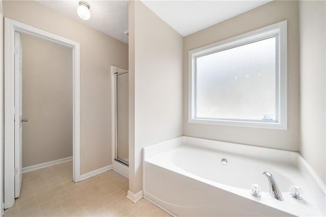 bathroom featuring a stall shower, a textured ceiling, a bath, baseboards, and tile patterned floors