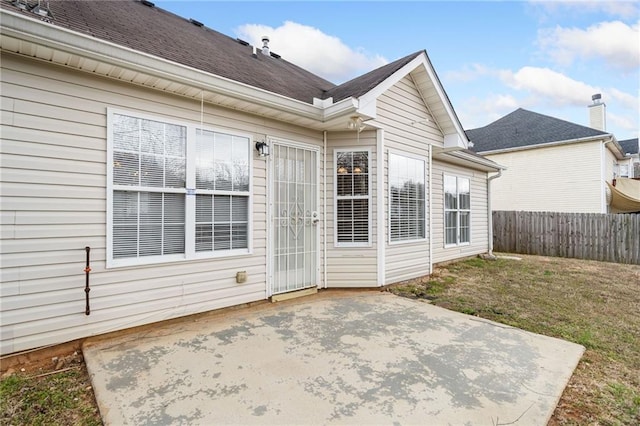 back of property featuring a patio area, a shingled roof, fence, and a lawn