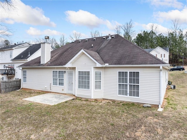 back of property featuring a shingled roof, a lawn, a patio, a chimney, and fence