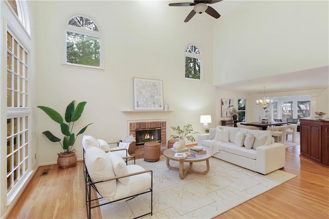 3711 Spinnaker Cir, Alpharetta, GA 30005 - living room with a high ceiling, a fireplace, light wood-style floors, a chandelier, and ceiling fan