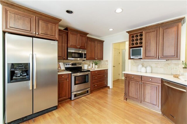 3711 Spinnaker Cir, Alpharetta, GA 30005 - kitchen with stainless steel appliances, tasteful backsplash, light wood-style floors, ornamental molding, and light countertops