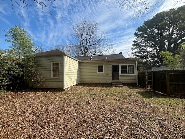 rear view of house featuring entry steps and fence