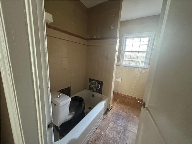 full bath with a tub, tile walls, and toilet