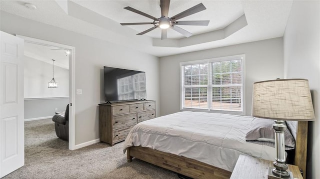 bedroom with a tray ceiling, carpet floors, baseboards, and ceiling fan