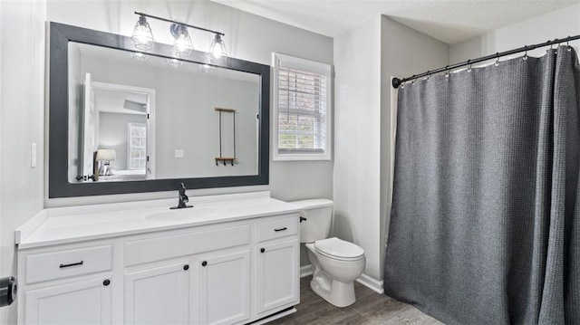 bathroom featuring toilet, vanity, a shower with curtain, wood finished floors, and a textured ceiling