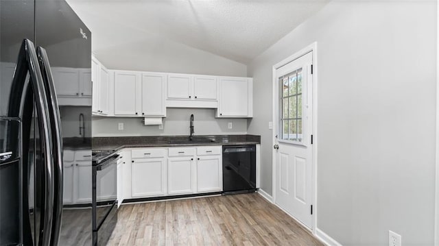 kitchen with lofted ceiling, light wood-style flooring, a sink, black appliances, and white cabinetry