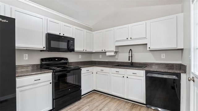 kitchen featuring dark countertops, white cabinets, black appliances, and a sink