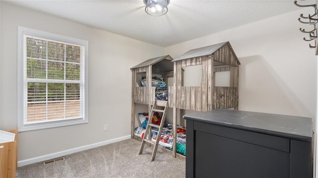 carpeted bedroom with visible vents, a textured ceiling, and baseboards