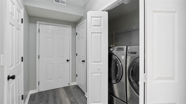 washroom featuring visible vents, washer and clothes dryer, dark wood finished floors, baseboards, and laundry area