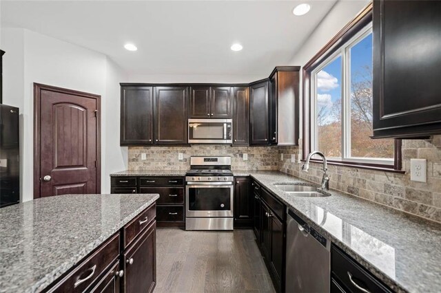 kitchen with light stone countertops, stainless steel appliances, dark wood-type flooring, and sink